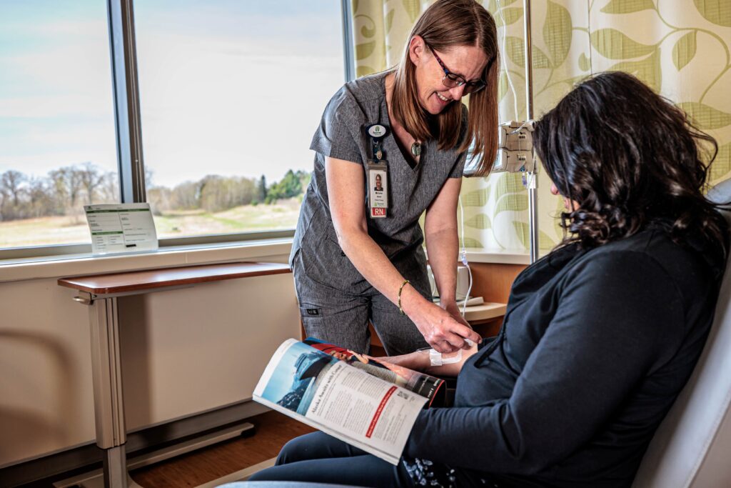 Healthcare professional administering infusion therapy to patient in comfortable treatment room, emphasizing local access to chronic condition management at Spooner Health.
